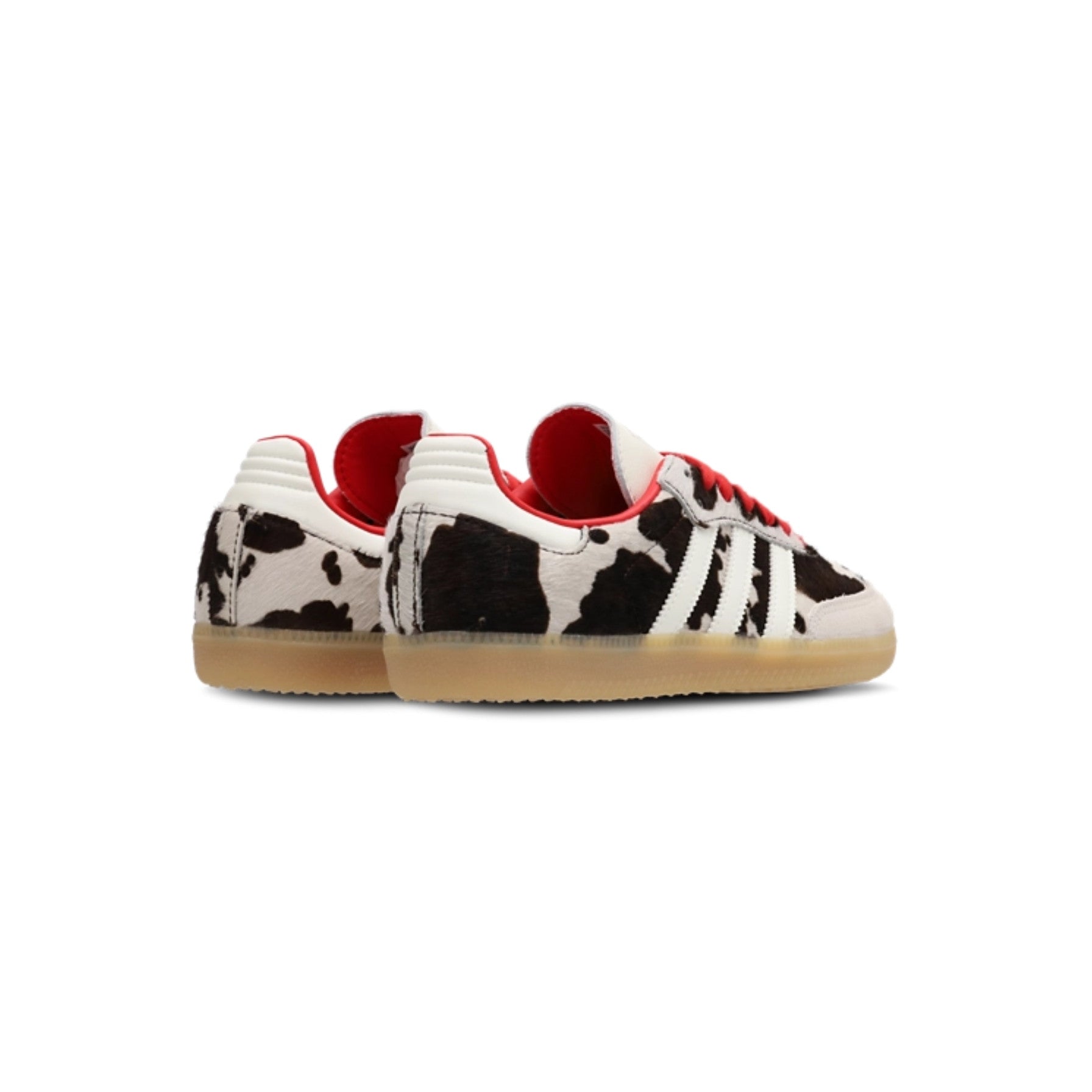 Pair of black and white cow print sneakers with red accents on a white background