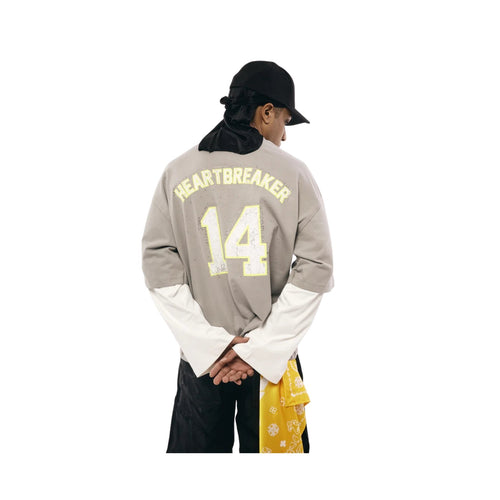 Person wearing a gray long-sleeve shirt with 'HEARTBREAKER 14' text on a white background