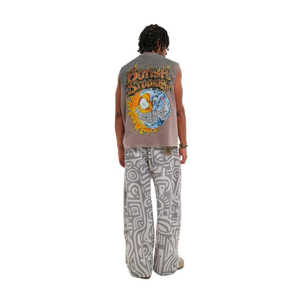 A person shown from the back wearing a sleeveless taupe-gray t-shirt with a large colorful 'Outsktream' graphic and wide-leg gray pants with a white geometric pattern, set against a plain white background.