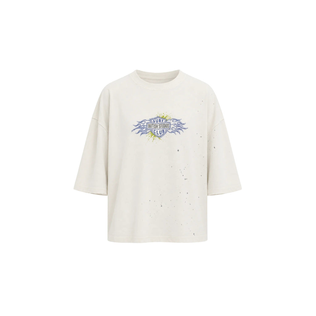 An oversized off-white t-shirt with a distressed, speckled texture and a central graphic print featuring the text 'STUDIES FROM THE BLOOD SHED' in blue and yellow.
