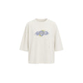 An oversized off-white t-shirt with a distressed, speckled texture and a central graphic print featuring the text 'STUDIES FROM THE BLOOD SHED' in blue and yellow.