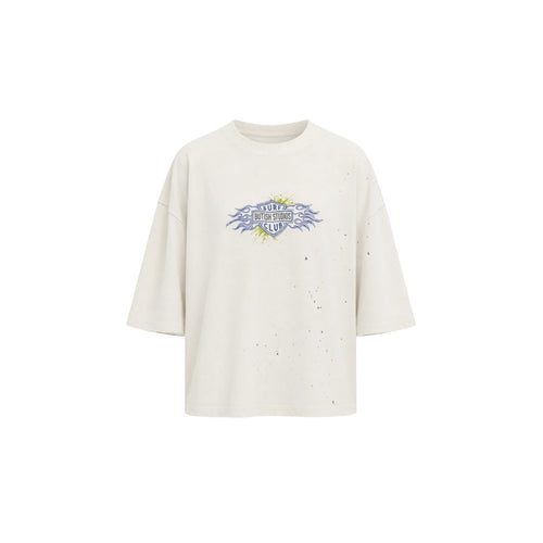 An oversized off-white t-shirt with a distressed, speckled texture and a central graphic print featuring the text 'STUDIES FROM THE BLOOD SHED' in blue and yellow.