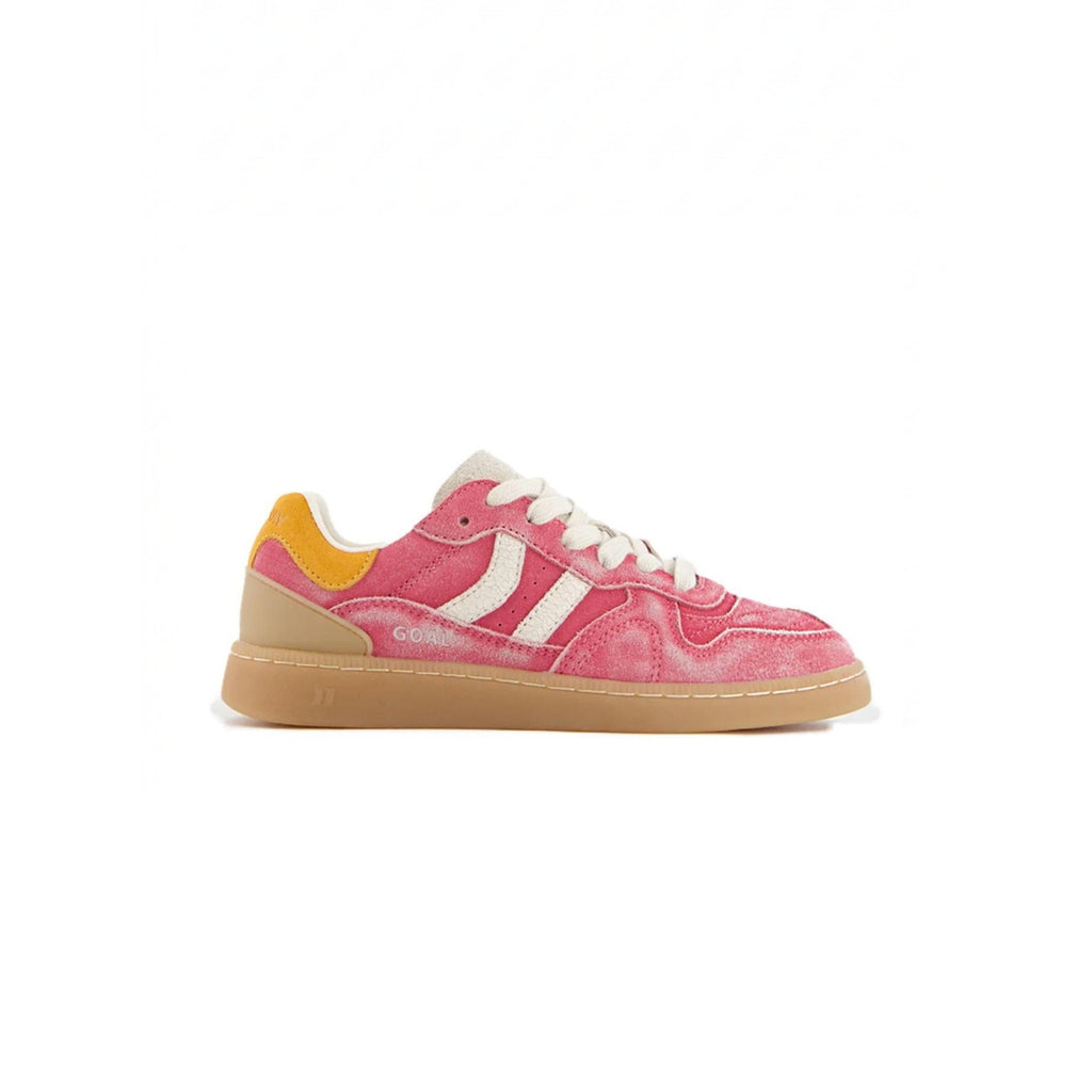 A low-top sneaker in pink suede with white side stripes, a yellow heel tab, white laces, and a gum-colored sole, shown from a side profile on a white background.