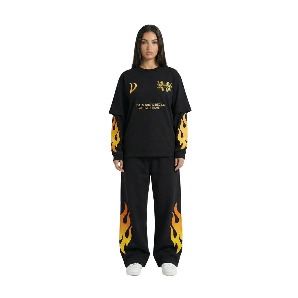A model wearing a black two-piece lounge set featuring a long-sleeve t-shirt and matching sweatpants, both decorated with yellow and orange flame graphics and gold text on the chest, set against a plain white background.