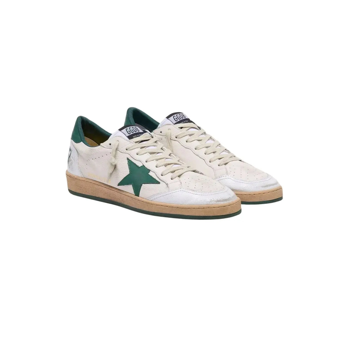 A pair of distressed vintage-style low-top sneakers, featuring off-white leather with a prominent green star on the side, dark green lining, and a tan rubber sole.