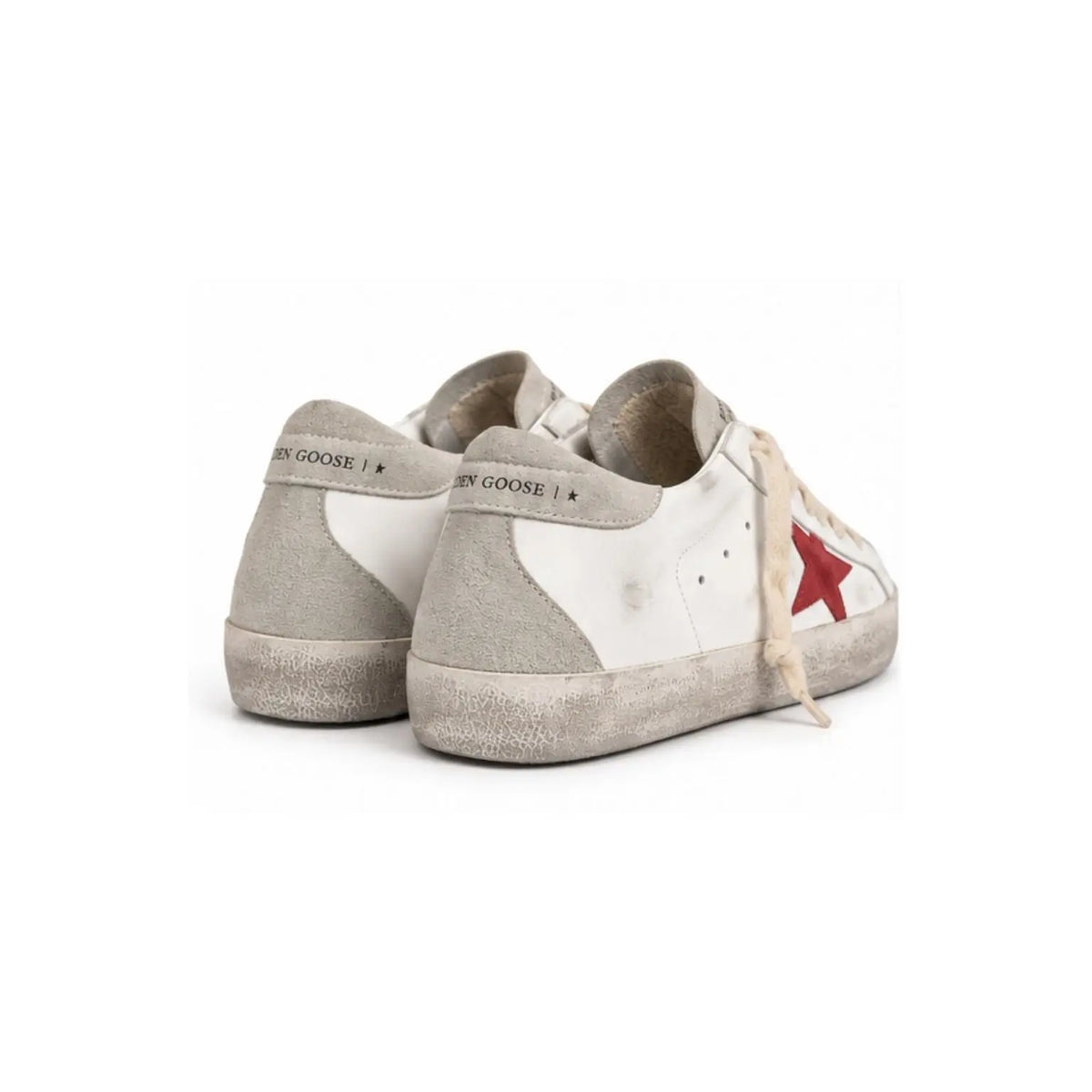 A pair of Golden Goose sneakers in a distressed off-white and light gray suede finish, featuring a signature red star on the side and light beige laces, set against a plain white background.