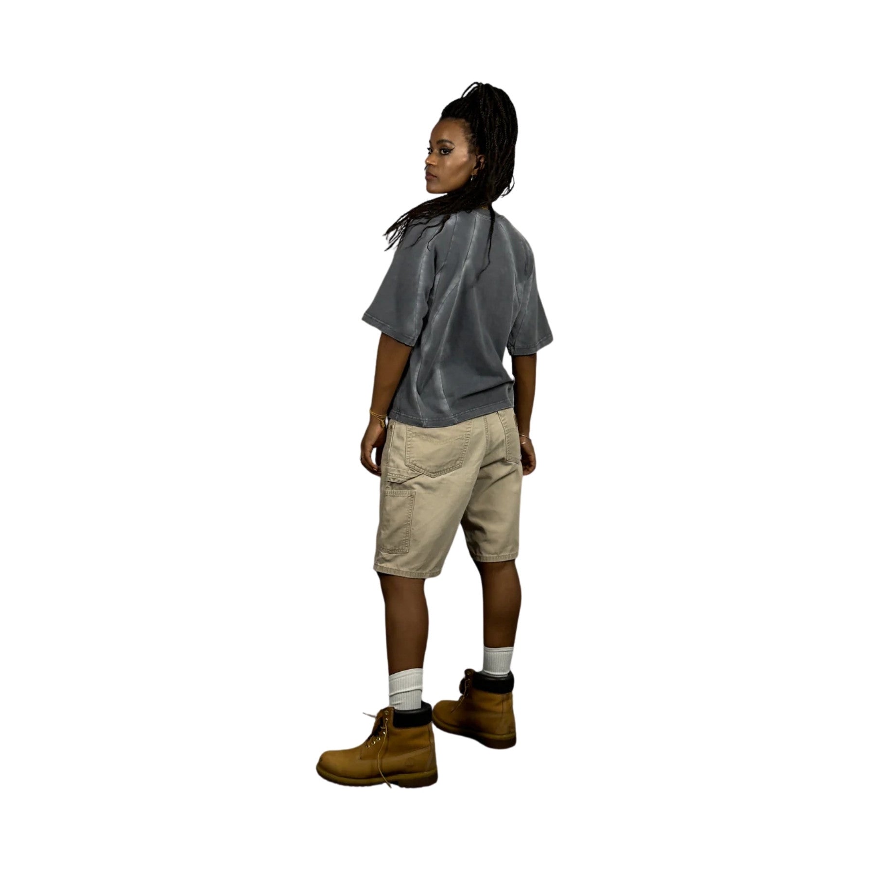 Person wearing a gray shirt, beige shorts, and brown boots on a white background