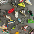 Collection of variously designed shoe keychains on a gray surface