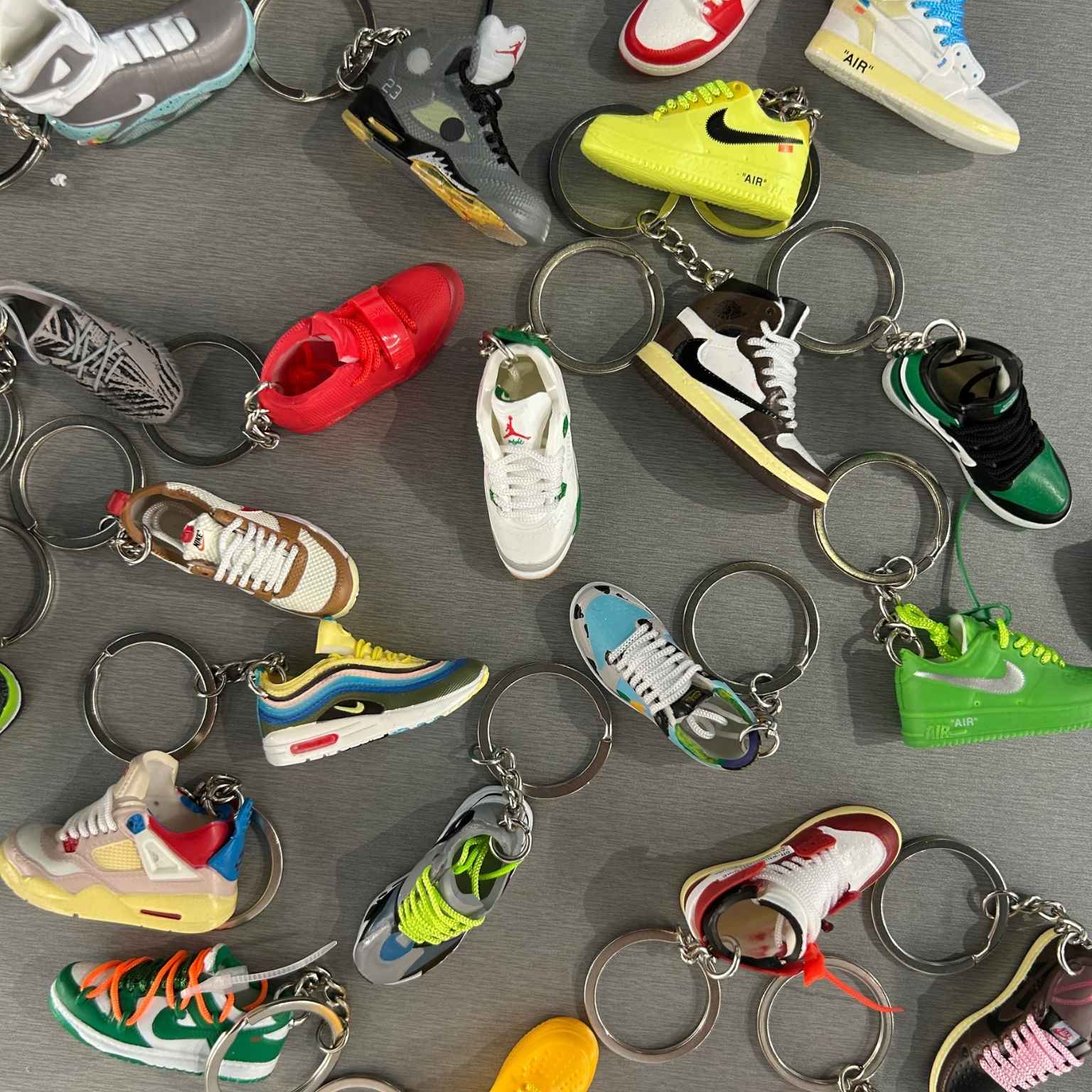 Collection of variously designed shoe keychains on a gray surface