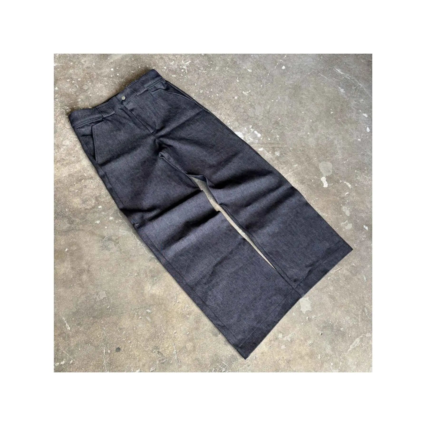 Dark blue jeans laid flat on a concrete surface