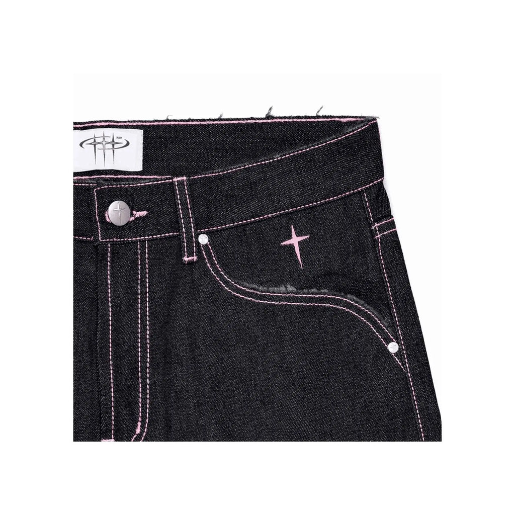 Close-up of black denim jeans with pink stitching on a white background