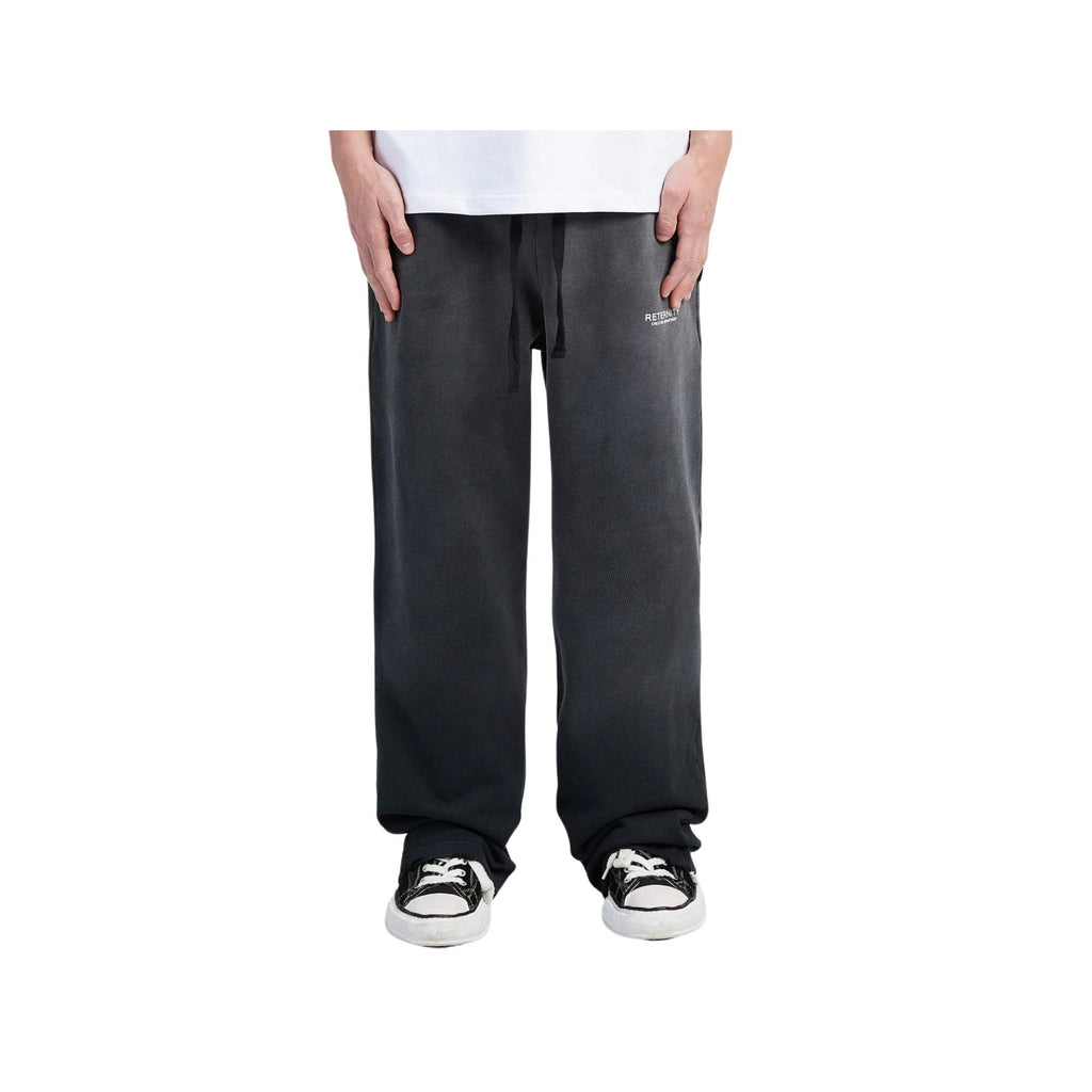 Person wearing black pants and black and white sneakers on a white background