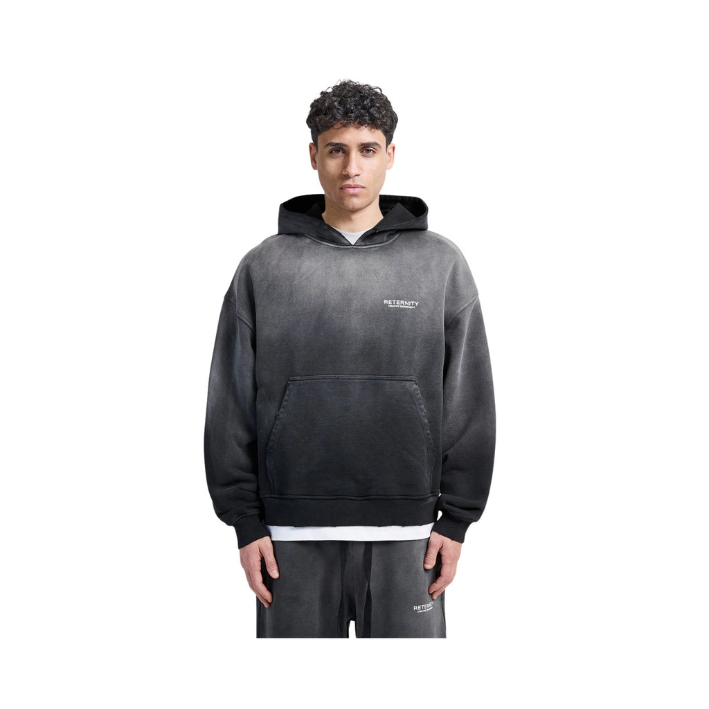Person wearing a black hoodie with a brand logo on a white background