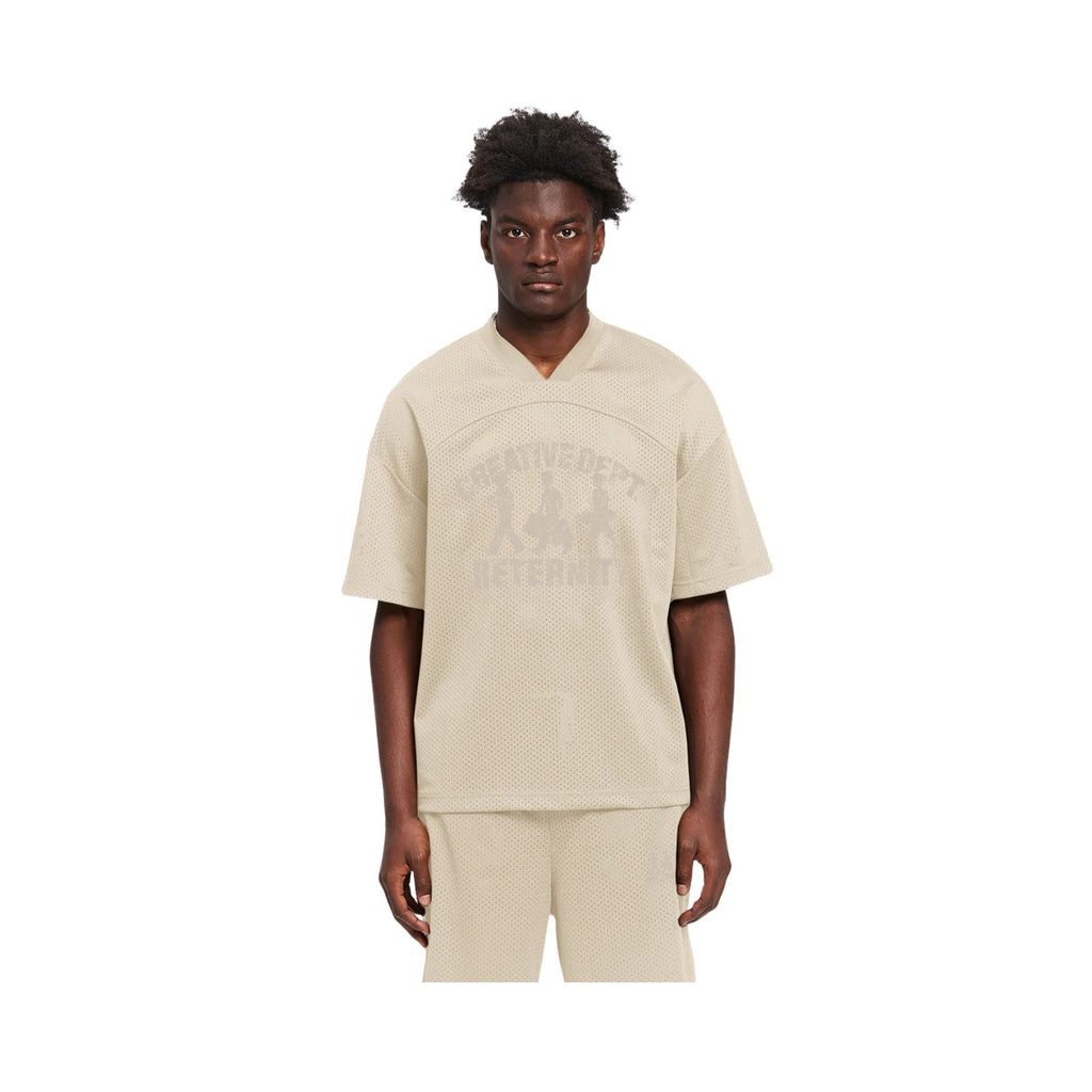 Person wearing a beige outfit with a brand logo on a white background