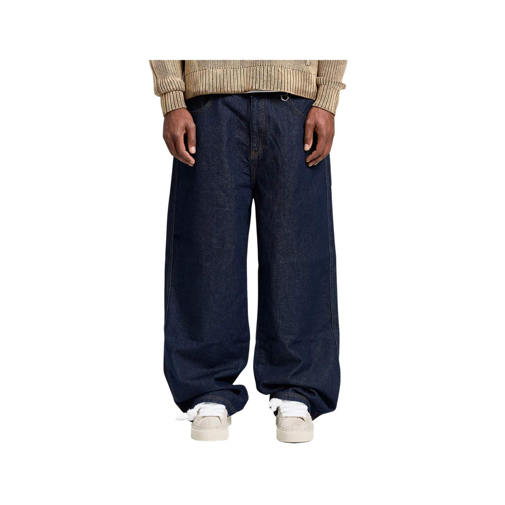 Person wearing dark blue wide-leg jeans and a beige sweater on a white background