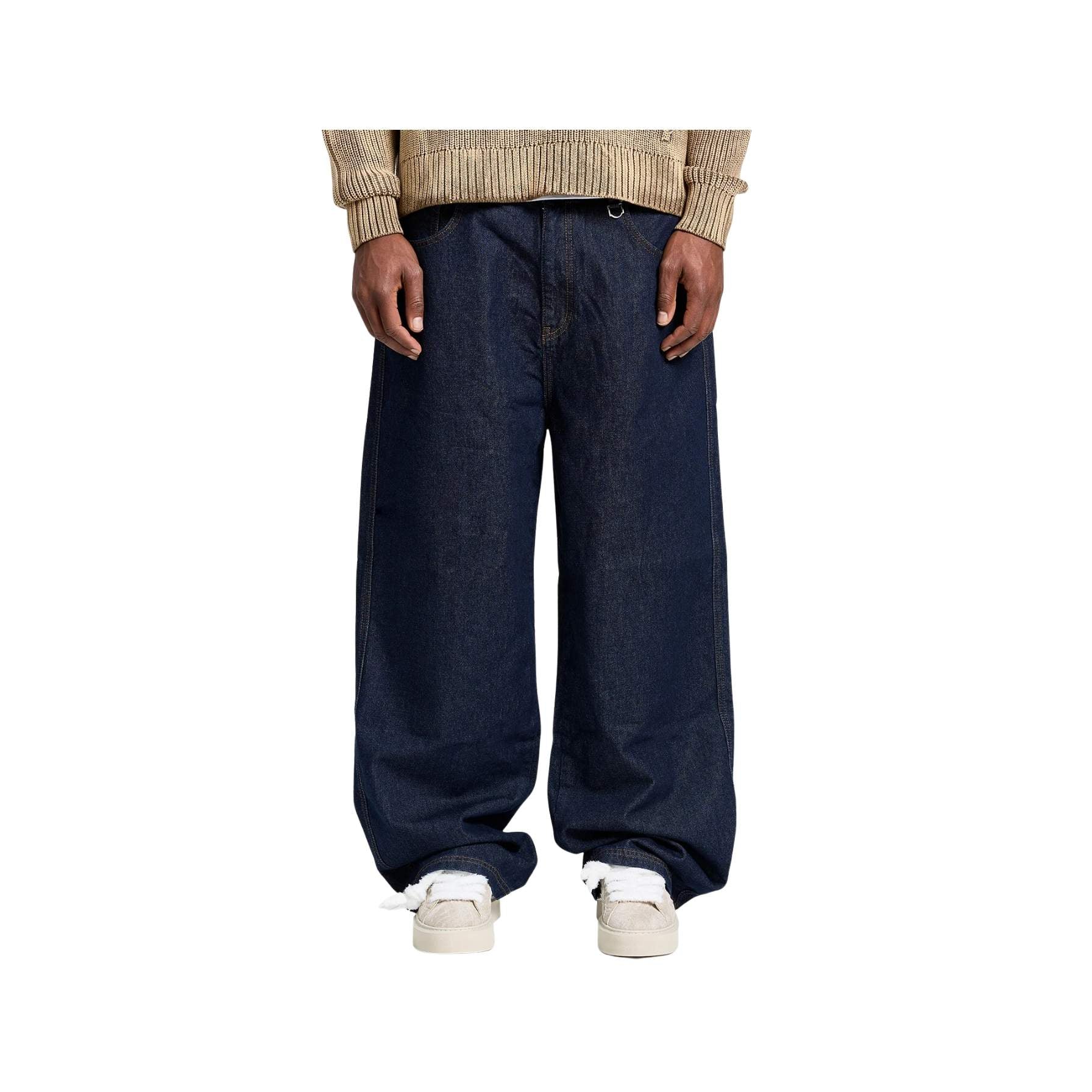 Person wearing dark blue wide-leg jeans and a beige sweater on a white background