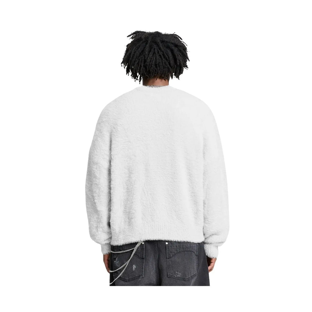 A person shown from the back wearing a fuzzy white long-sleeve sweater and dark gray jeans against a plain white background.