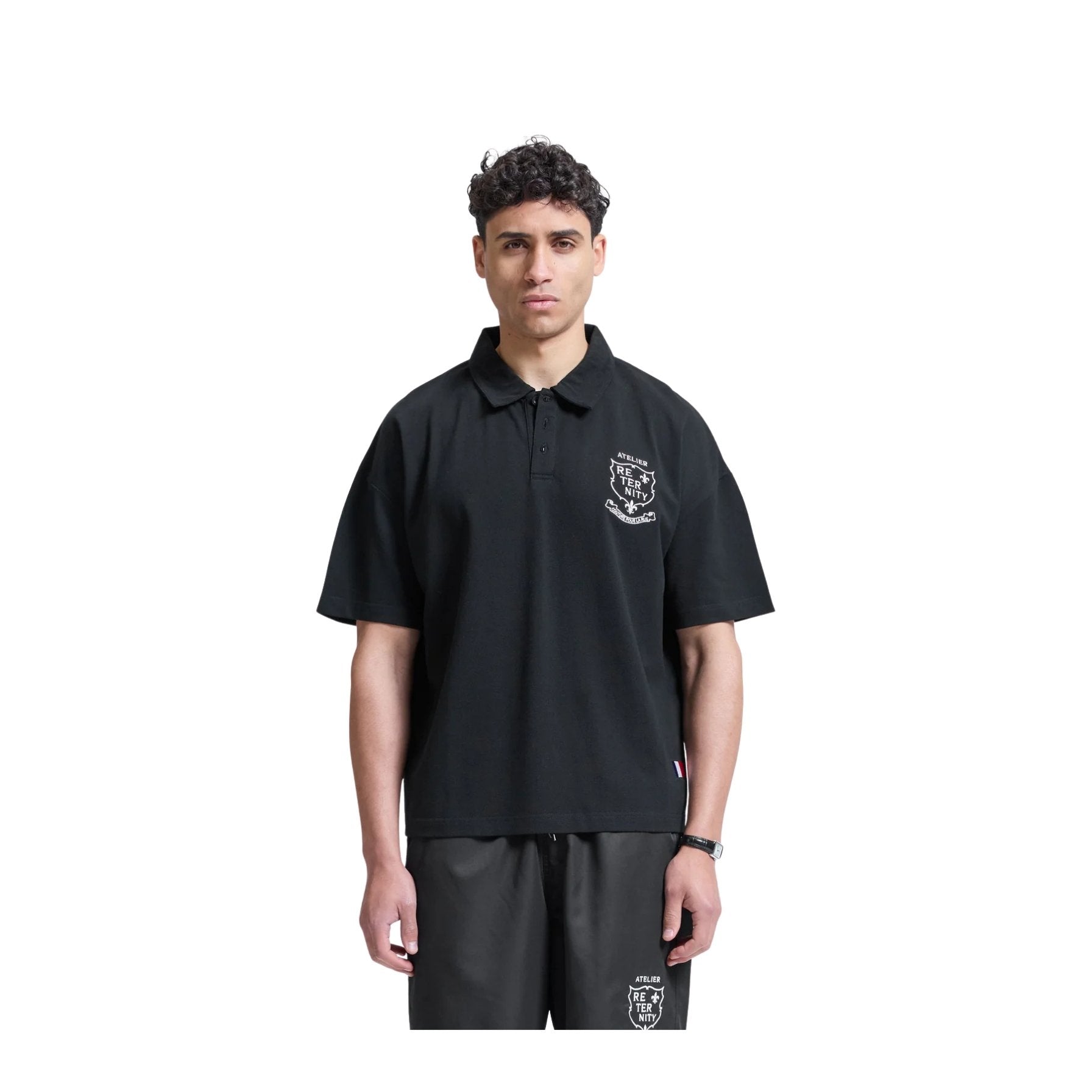 Person wearing a black polo shirt with a logo on a white background