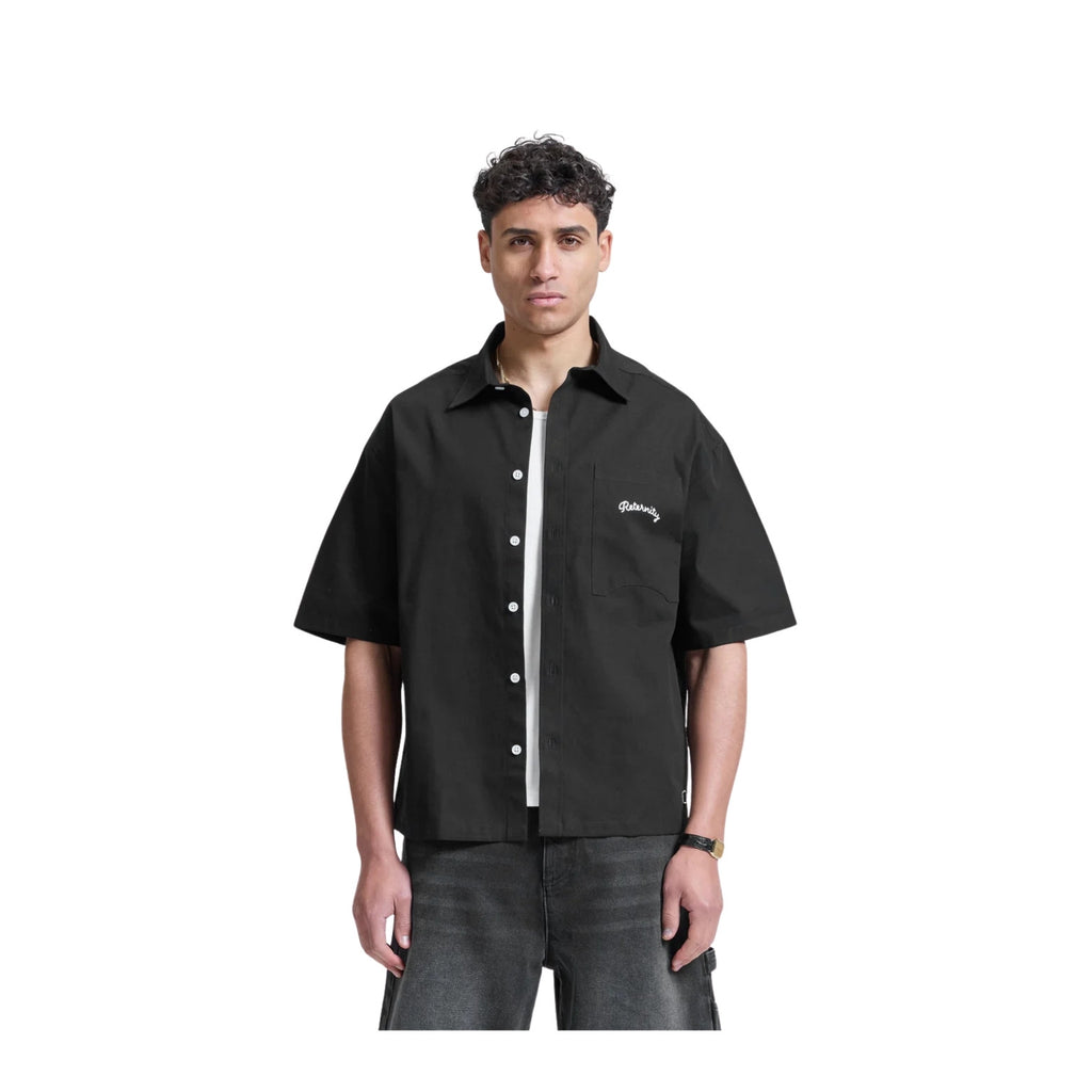 Person wearing a black short-sleeve shirt with a brand logo on a white background