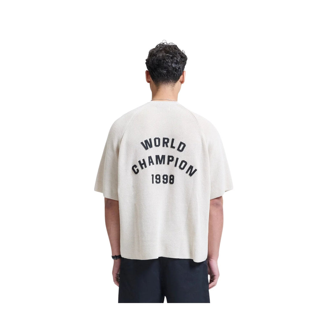 Person wearing a white t-shirt with 'World Champion 1998' text on the back, standing against a white background.